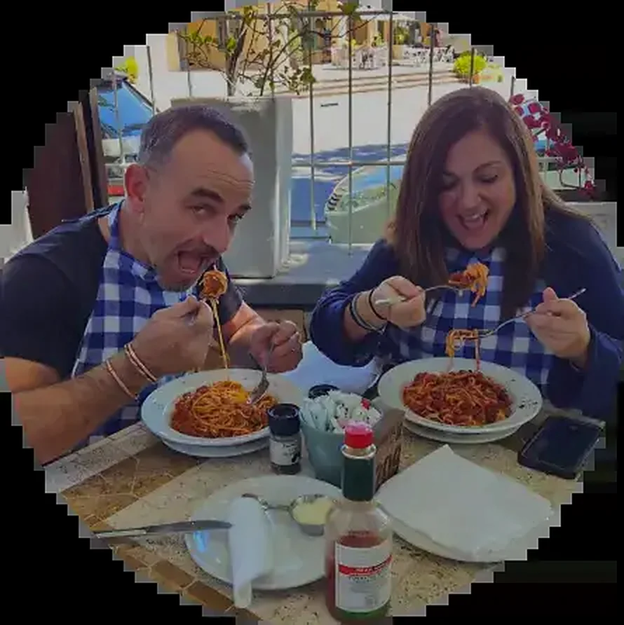 Dario and Rossella in blue gingham bibs, tucking into spaghetti