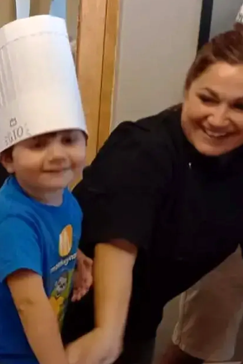 A little chef in a paper hat rolling dough with a smiling helper at Dario's