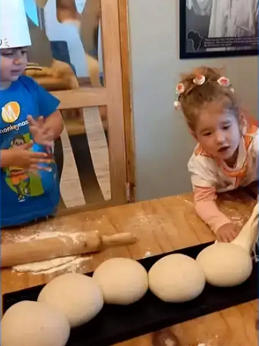 Two young chefs eyeing a tray of dough balls at a Dario's pizza party